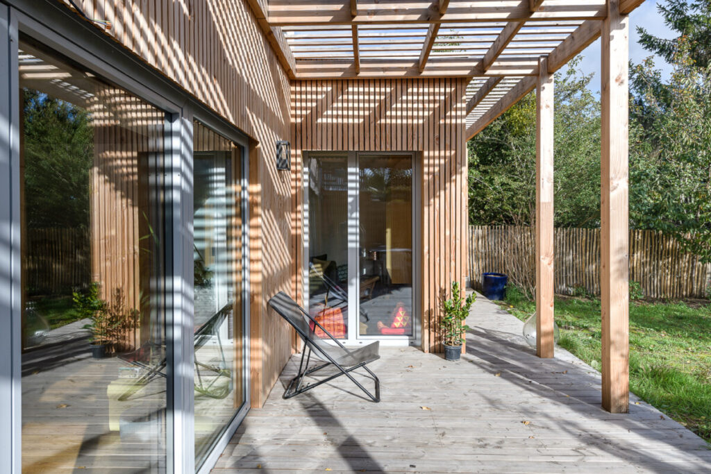 La terrasse en bois est ombragé par la pergola.