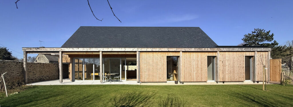 façade maison passive bois et toiture ardoises dans un jardin ensoleillé